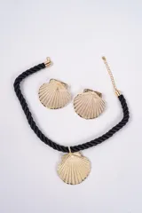 Set compuesto por un collar de cordón trenzado negro con dije central en forma de concha dorada y un par de aros a juego con diseño de concha dorada.