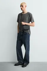 Bandolera pequeña de color negro con cuerpo rectangular y textura trenzada en el frente. Posee un asa de hombro ajustable y extraíble.