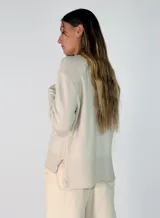 Sweater de punto color negro, con cuello redondo, manga larga y diseño con costura central vertical. Presenta un dobladillo acanalado en la cintura y puños, con un largo asimétrico siendo más corto en la parte delantera y más largo en la parte trasera.