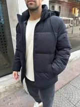 Campera puffer de gamuza negra con capucha desmontable forrada en corderito, cierre frontal y bolsillos laterales.