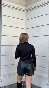 Polera negra de manga larga confeccionada en jersey térmico, con diseño asimétrico y ajuste al cuerpo.