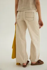 Pantalón de corte recto y tiro medio con costuras a la vista, bolsillos delanteros y traseros, y un detalle de pin de la marca en el ruedo.