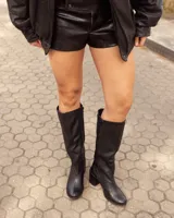 Bota de caña alta de cuero color negro, de diseño clásico con taco ancho y puntera redondeada.