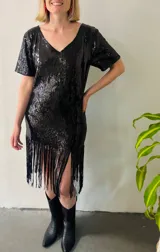 Vestido corto negro de lentejuelas con escote en V, mangas cortas y flecos en el ruedo.