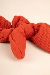 Gomita de pelo tipo scrunchie color verde salvia, con textura arrugada y moña con forma de orejas de conejo.