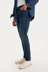 Jean de denim azul oscuro, corte slim taper, tiro medio, con cierre de cremallera y cinco bolsillos.