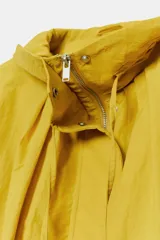 Cazadora bomber de cuello subido ajustable con cordones, manga larga con puños elásticos y cierre frontal con cremallera y botones a presión ocultos bajo solapa. Cuenta con bolsillos delanteros y diseño holgado.