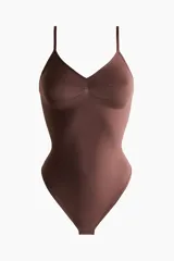 Body tanga de color marrón oscuro, con efecto vientre plano y copas forradas sin aros con sección en punto menguado para realzar el busto. Posee breteles ajustables y refuerzo interior con botones a presión ocultos.