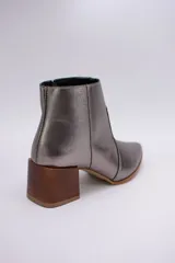 Botas cortas de cuero color beige, con punta fina y cierre lateral. Tienen un taco cuadrado de madera.