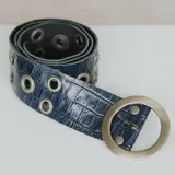 Cinto azul con textura símil cocodrilo, hebilla circular metálica y ojales metálicos.