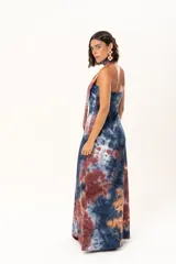 Vestido largo de corte recto y escote strapless, con estampado estilo batik en tonos azul, naranja y bordó. Incluye una bufanda larga integrada al diseño que cae desde el cuello.
