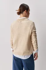 Sweater de punto color verde militar, con cuello polo y cierre frontal de botones, de manga larga con puños elastizados y diseño texturizado con relieve geométrico.