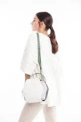 Bolso bandolera de cuero sintético blanco, lila y verde, con forma hexagonal y correa larga verde ajustable.