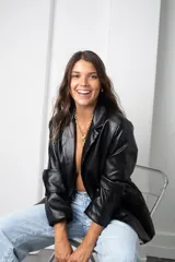 Blazer de eco cuero negro con hombreras, solapas clásicas y cierre frontal con botones.