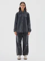 Camisa de denim de corte recto y estilo clásico, confeccionada en tejido de algodón con acabado lavado. Presenta cuello camisero, cierre frontal con botones metálicos y mangas largas con puños abotonados.