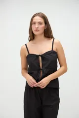 Top de pijama blanco confeccionado en algodón, con tirantes finos, escote recto y aberturas frontales con lazos ajustables.
