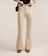 Pantalón flare negro de punto roma con detalle metálico en la cintura y cierre delantero.