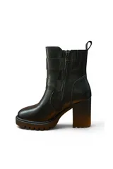 Bota alta de cuero negro con plataforma track, taco ancho y dos tiras con hebillas metálicas plateadas en el lateral.