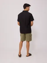 Camisa de manga corta color negro, con cuello clásico y cierre frontal de botones.