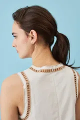 Blusa sin mangas de corte crop en color blanco, con detalles de bordados calados en tono tostado formando diseños florales en el cuello, los hombros y el borde inferior.