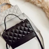 Cartera bandolera negra de ecocuero con diseño acolchado en rombos. Tiene asa corta superior y correa larga desmontable y regulable.