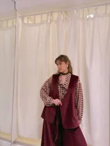 Chaleco largo de terciopelo color bordó, con corte recto y sin cierre.