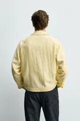 Sobrecamisa relaxed fit de color amarillo claro, confeccionada en tejido con mezcla de lyocell. Presenta cuello solapa, mangas largas raglán con puños abotonados, bolsillos de vivo en la cadera y cierre frontal con botonadura.