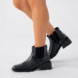 Bota corta tipo chelsea de cuero vacuno color negro, con puntera cuadrada, taco cuadrado de madera y detalle de textura grabada en el panel elástico lateral.