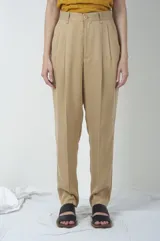 Pantalón de vestir color beige, de corte recto, con pinzas en la parte delantera y cierre con botón.