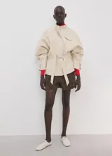 Chaqueta beige de cuello alto, manga larga con puños abotonados, bolsillo con solapa en el pecho, cinturón ajustable para la cintura y cierre frontal de cremallera oculta.