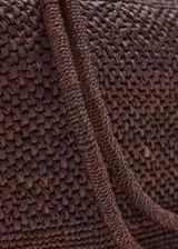 Bolso tipo shopper color marrón, confeccionado en paja trenzada con dos asas largas para llevar al hombro.