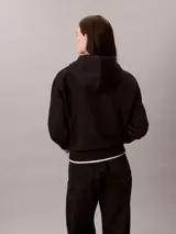 Buzo con capucha Calvin Klein de corte clásico, confeccionado en mezcla de algodón y poliéster. Presenta cordones ajustables en la capucha, puños y dobladillo con terminación en punto canalé, y el logotipo de la marca bordado de forma sutil en el pecho.