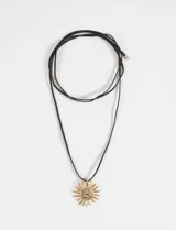 Collar de cordón negro con dije metálico en forma de sol con textura grabada en color dorado.