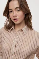 Camisa de rayas de calce relajado, confeccionada en tejido liviano y semitransparente, con cuello clásico, cierre frontal con botones, mangas largas con puños y hombros caídos.