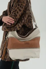 Bolso tipo hobo de cuero color beige con panel central de gamuza color terracota. Tiene correa de hombro regulable, forro interior de tela con bolsillo con cierre y bolsillo para celular. El panel frontal tiene dos bolsillos con cierre metálico.