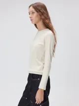 Remera de manga larga con cuello a la base, confeccionada en tejido de punto acanalado color beige. Presenta un logo bordado en el centro del pecho.