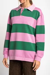 Sweater tipo polo de manga larga con diseño de rayas horizontales anchas en color rosa y gris. Presenta cuello camisero con cierre frontal de botones y puños elásticos.