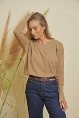 Buzo tejido color camel, de manga larga, escote en V y tajitos en los costados.