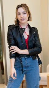 Chaqueta corta negra de cuero sintético, con cuello clásico, cierre frontal asimétrico con cremallera y bolsillos laterales con cremallera.