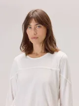 Remera de manga larga color blanco con cuello redondo. Presenta un detalle de costura con vivo horizontal en el pecho y en las mangas, aportando un diseño sutil y estructurado.