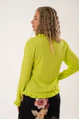 Blusa verde lima con textura arrugada, cuello redondo con volantes y mangas largas con puños elásticos.