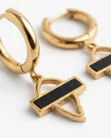 Caravanas tipo argolla de acero dorado con dije colgante geométrico que combina una estructura metálica con una barra central en color negro.