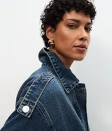 Campera bomber de jean azul oscuro, de corte corto con mangas globo, cuello con solapa y cierre frontal abotonado.