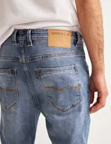 Pantalón jean celeste de corte slim fit, con arrugas en la parte superior de las piernas.