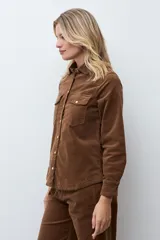Camisa de pana color tostado, con cuello clásico, cierre frontal con botones metálicos y bolsillos frontales con solapa.