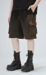 Bermuda estilo cargo oversize de algodón, con proceso de desgaste que genera un efecto degradado de negro a marrón óxido. Presenta recortes y bolsillos laterales con tapa.