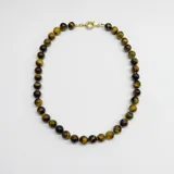 Collar de cuentas esféricas de piedra ojo de tigre de 10 mm, con separadores de nudos de hilo y cierre de mosquetón con baño de oro.