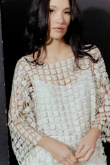 Blusa de red en color blanco con apliques de flores tridimensionales en toda la prenda. Presenta transparencias, cuello redondo y mangas largas.