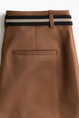 Pantalón bootcut color marrón, tiro alto, con pliegues frontales y cinturón elástico incluido con hebilla metálica redonda.