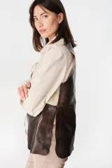 Chaleco de cuero marrón con interior y solapas de piel sintética color crudo. Diseño sin cierre, con corte recto y acabado texturizado.